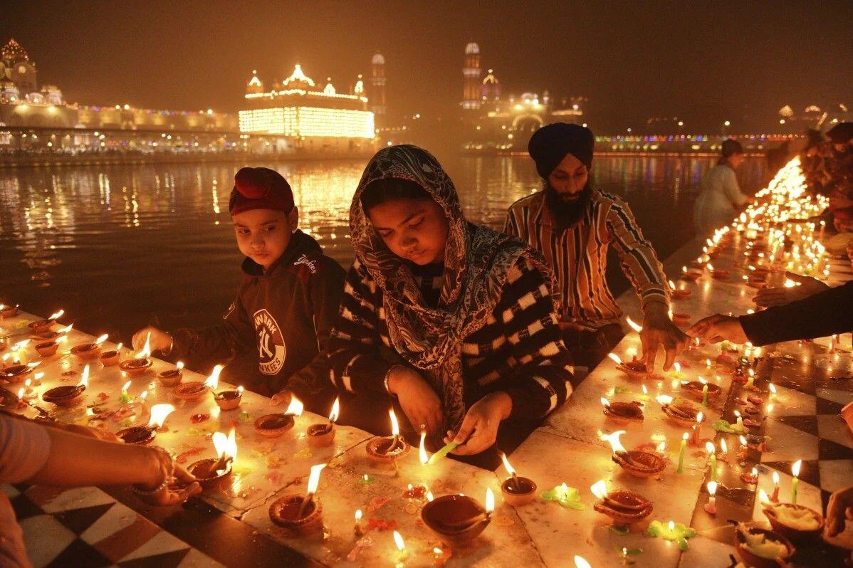 Sikh devotees light clay lamps next…